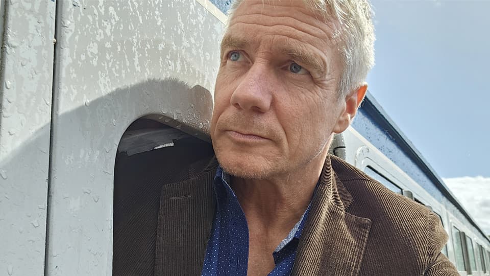 Professor Brian Haddock leans out of the window of a train carriage.